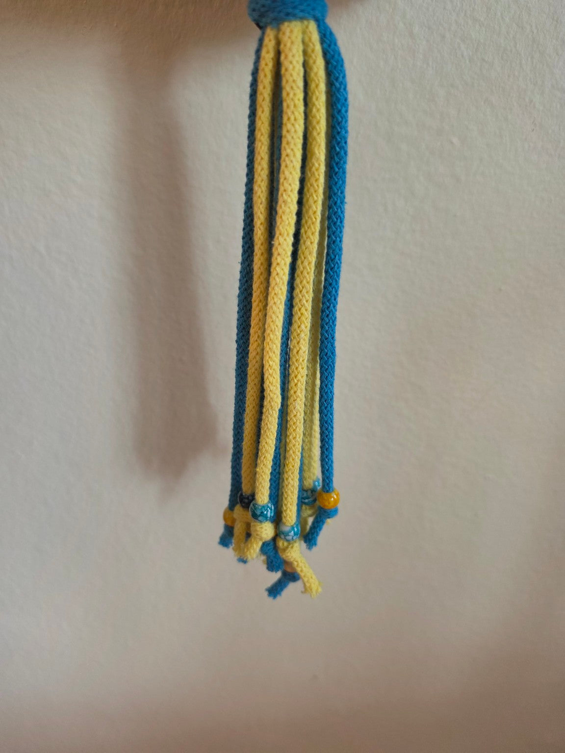 Close-up of decorative beads on the blue and yellow macrame tassel