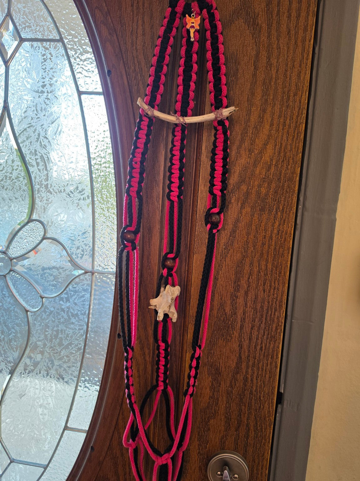 Full view of black and pink handmade macrame plant hanger with natural bone, vertebra, wooden beads and fairy charm