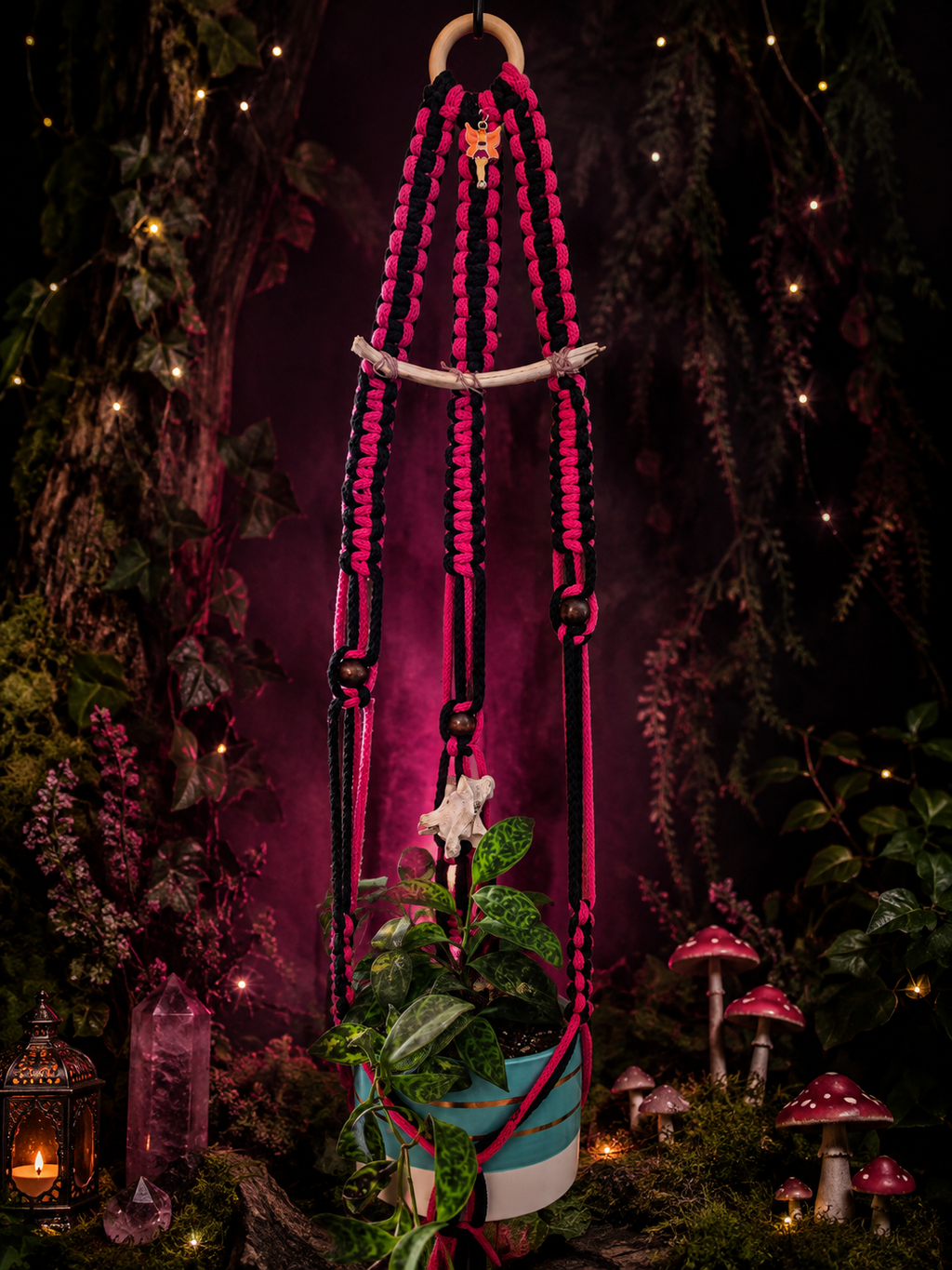 Black and pink handmade macrame plant hanger with bone accents, vertebra, fairy charm and potted plant in an enchanted woodland setting