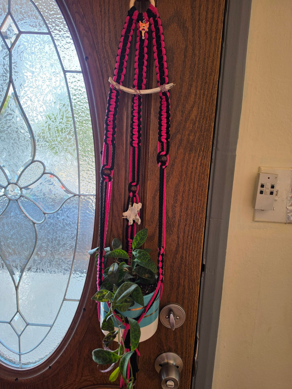 Handmade black and pink macrame plant hanger with bone accents, fairy charm and plant