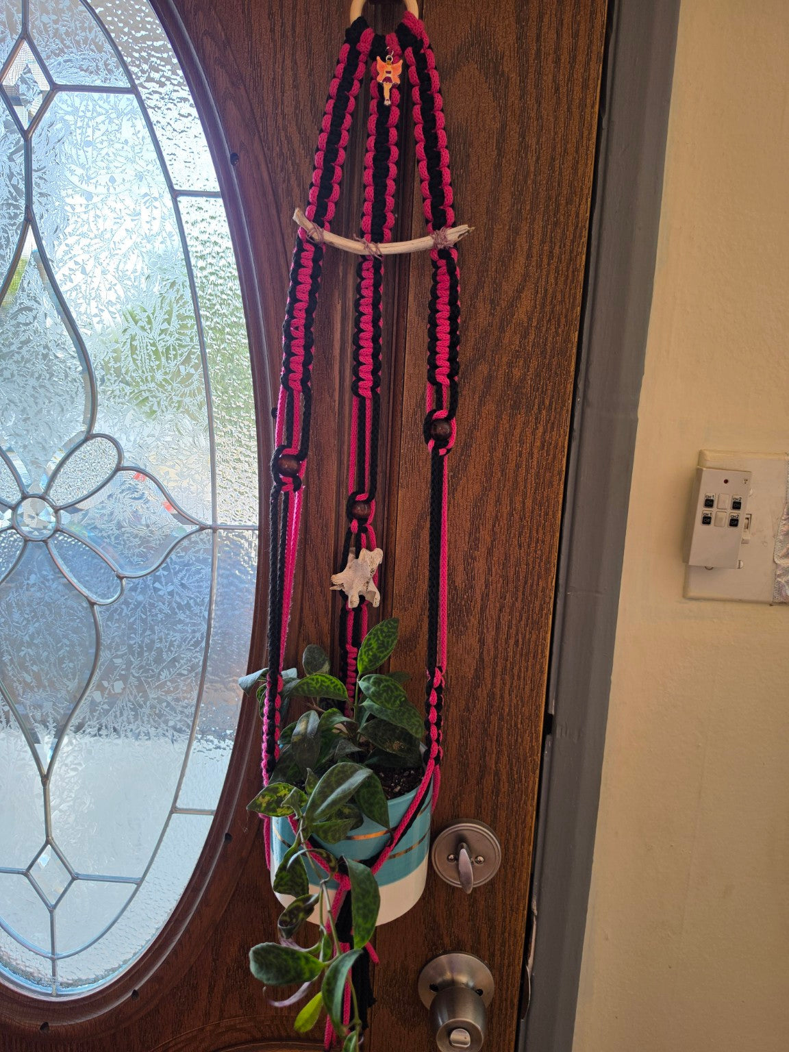 Handmade black and pink macrame plant hanger with bone accents, fairy charm and plant